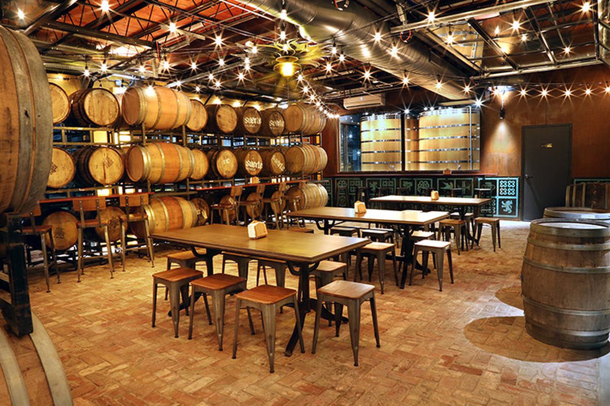 A brewery tasting room with kegs and tables.