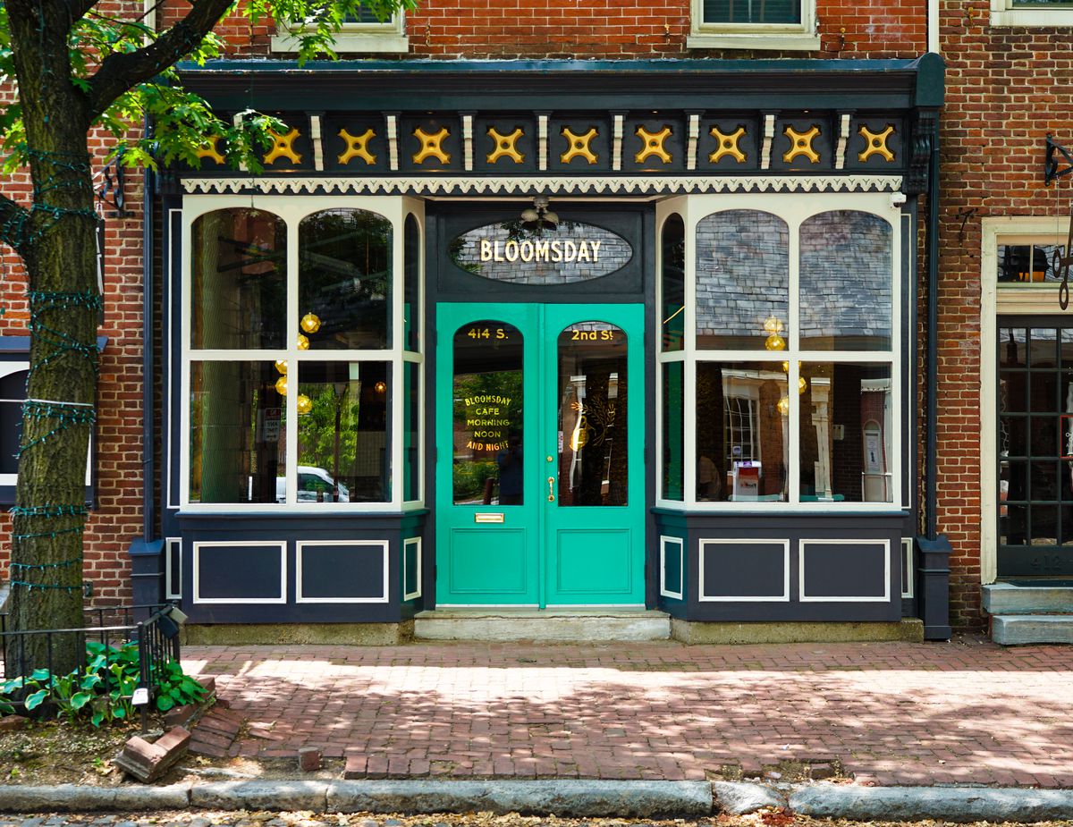 Bloomsday cafe front windows with a teal green door and a yellow and white overhang