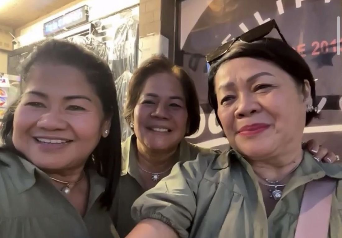 Three Asian women wear matching olive green blouses.