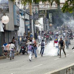 Opposition supporters and students clash with national guard soldiers and riot police firing tear gas as they protest near a highway in the Altamira neighborhood of Caracas, Venezuela, Monday, April 15, 2013.  National Guard troops dispersed students protesting the official results of Venezuela's disputed presidential election. Opposition candidate Henrique Capriles has challenged his narrow loss to Nicolas Maduro and is demanding a recount. (AP Photo/Ramon Espinosa)