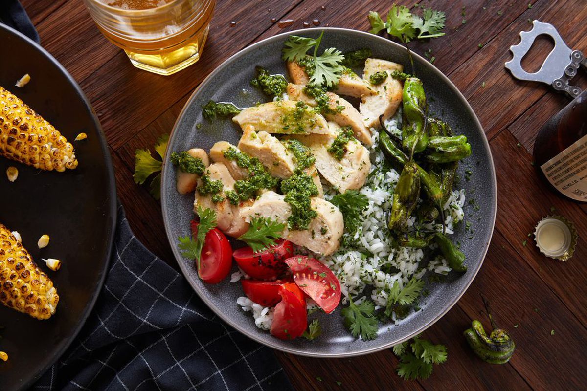 A plate of chicken pieces and greens on a table.