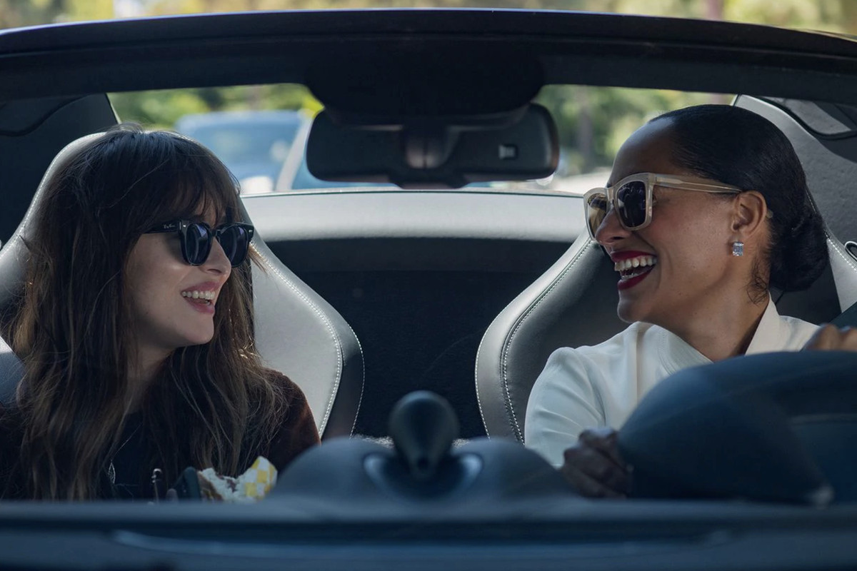 Two women smile at one another in a car.