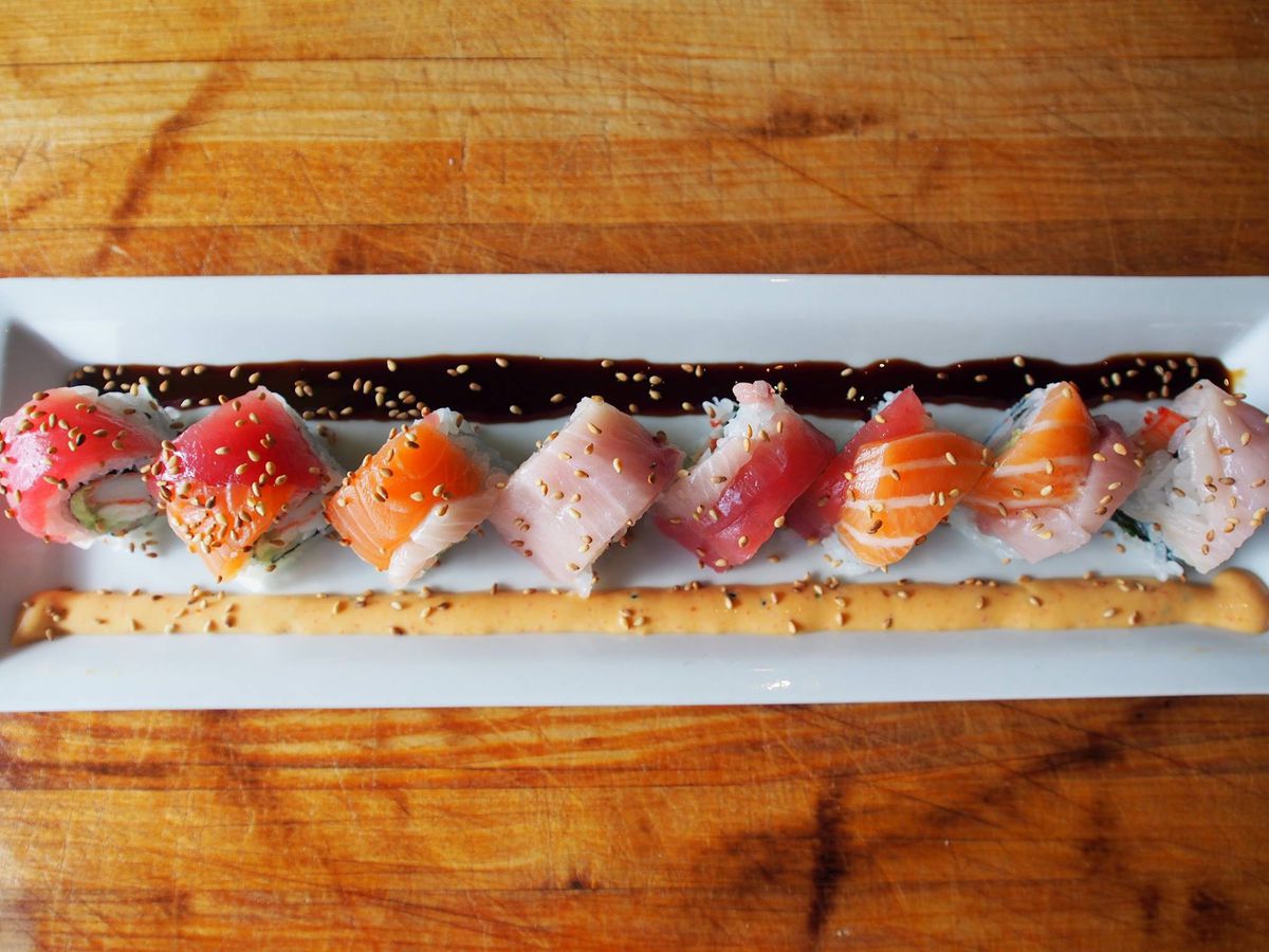 A long white plate with various sushi pieces.