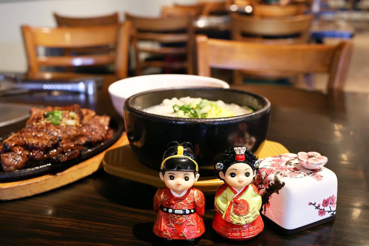 A bowl of soup behind two figurines.