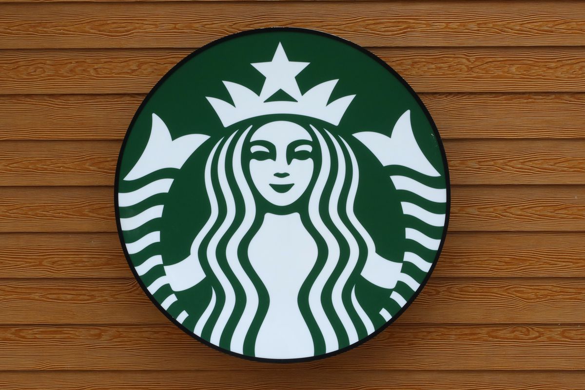 Green Starbucks logo hangs on a wooden wall.