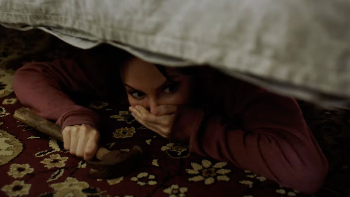 Yulia Klass sebagai Alys bersembunyi di bawah tempat tidur dengan palu di tangannya di Captors.