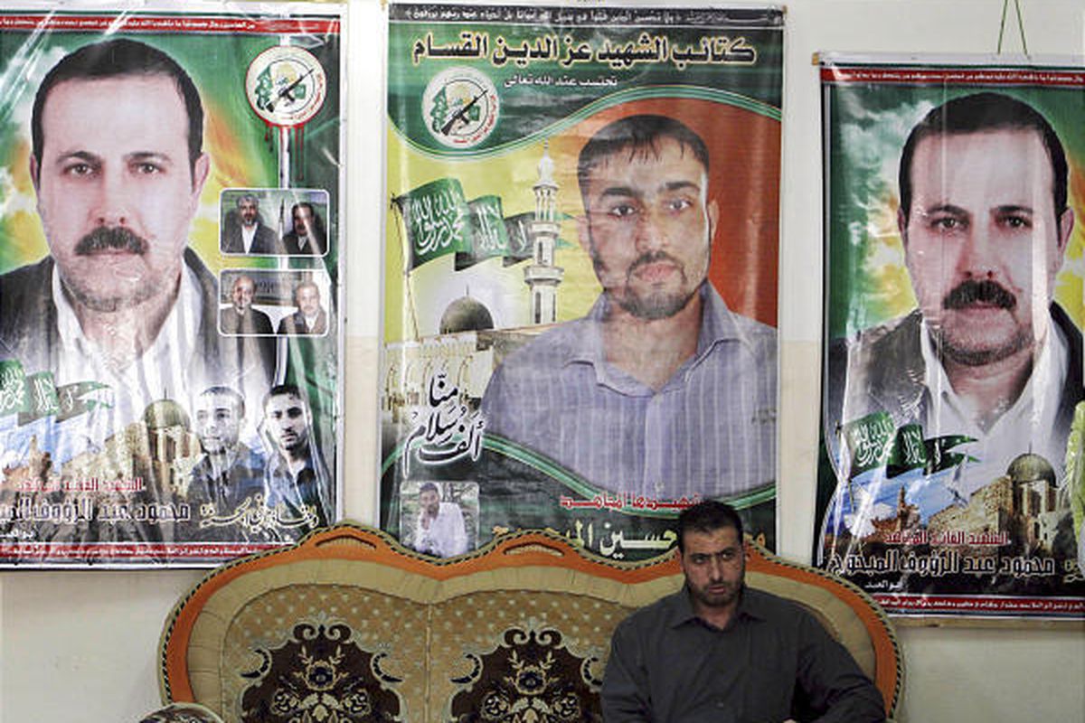 In this Tuesday, Feb. 16, 2010  file photo, Palestinian Fayeq al-Mabhouh sits in front of posters of his brother and Hamas commander Mahmoud al-Mabhouh, left and right, who was assassinated in Dubai, and Hamas member Mohammed Hussein Mabhouh, in the famil