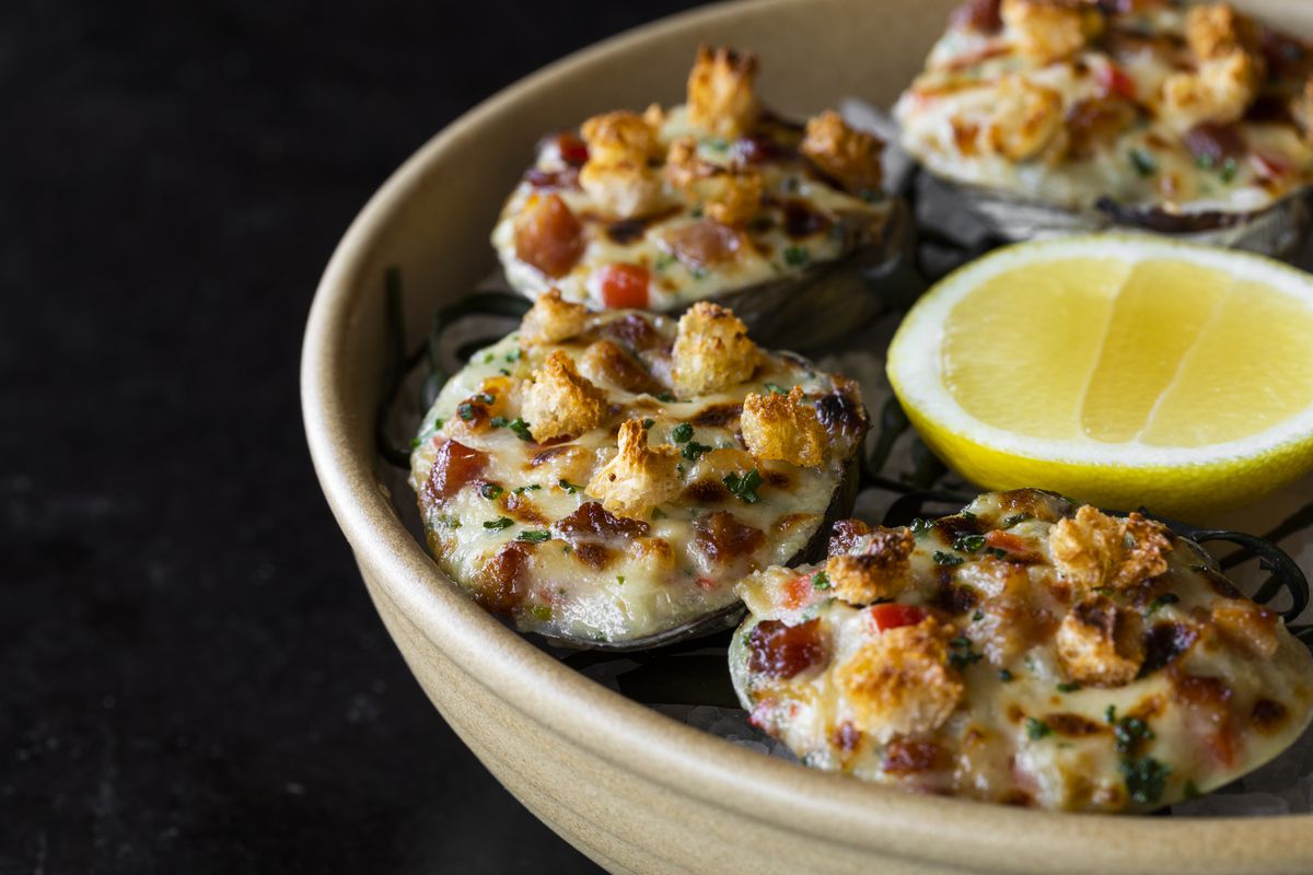 Navy Blue’s clams casino served on the half shell, topped with breadcrumbs, bacon, and peppers, with a side of lemon.