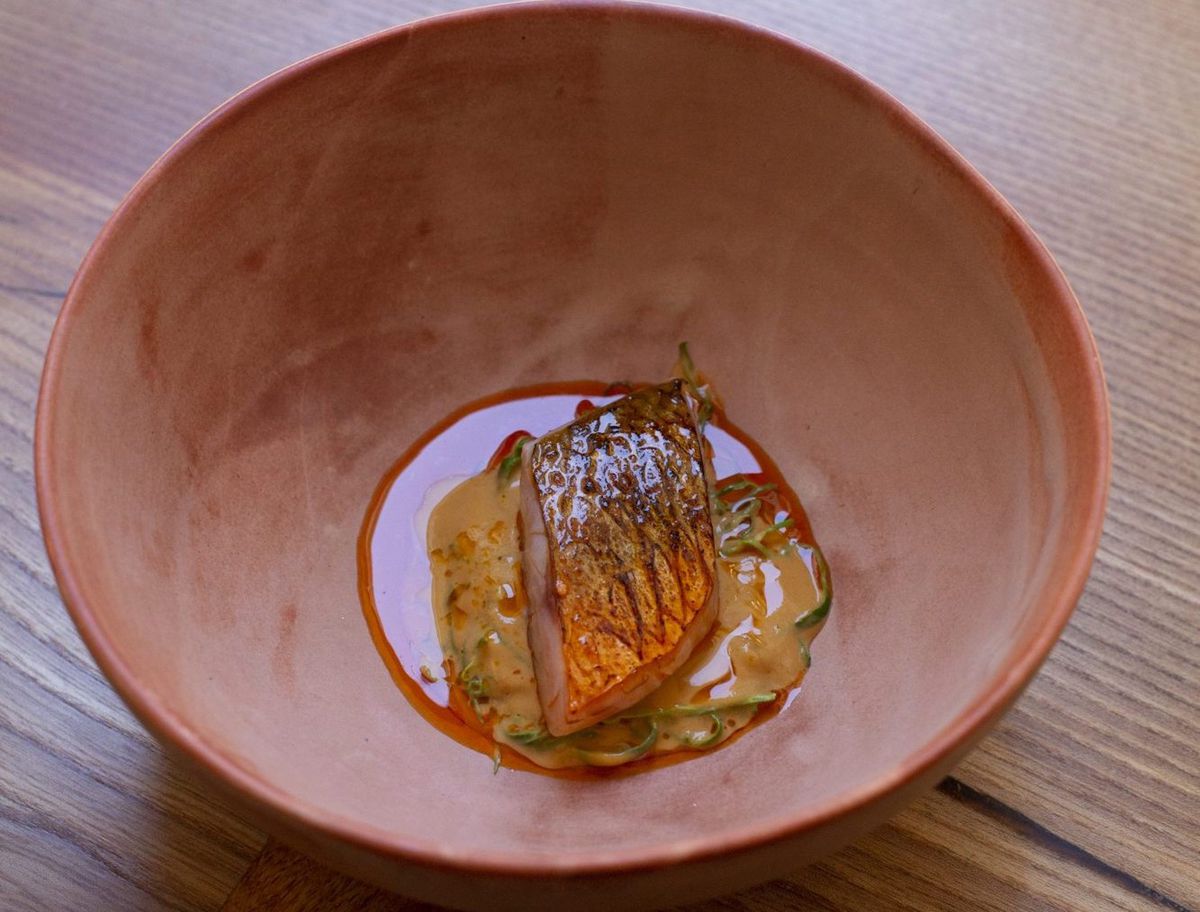 A pink-orange porcelain bowl filled with red mullet and red sauce at Ikoyi.