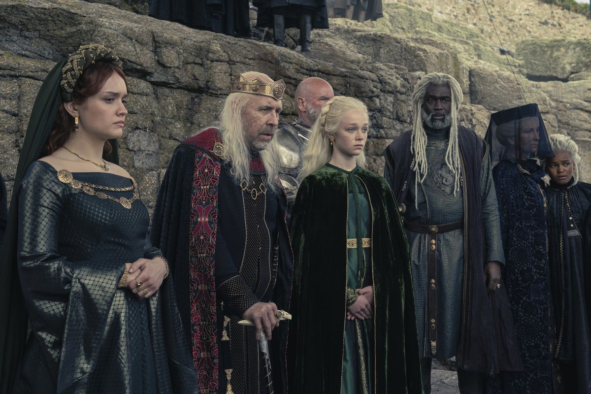 Alicent, Viserys, Helaena, Corlys, Rhaenys, and Baela standing in a row and looking somber