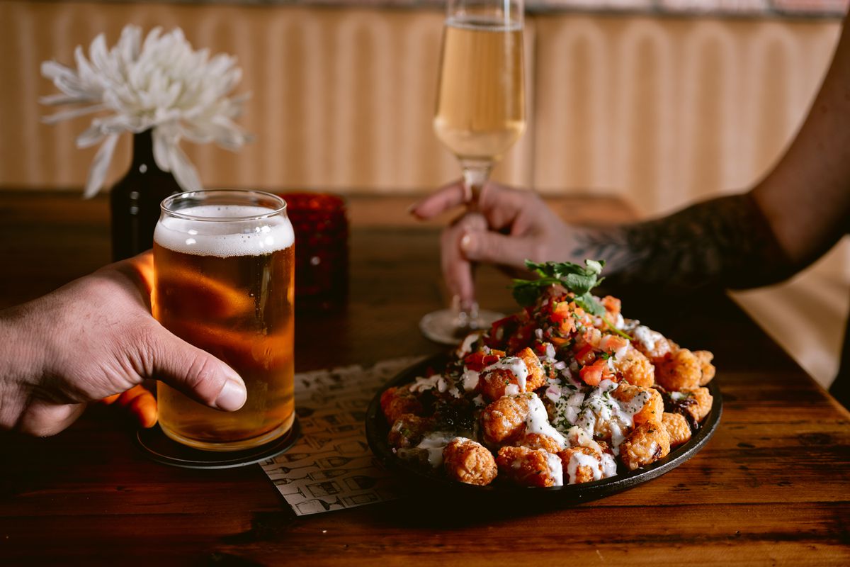 A plate of food is seen alongside a pint of beer and flute of Champagne