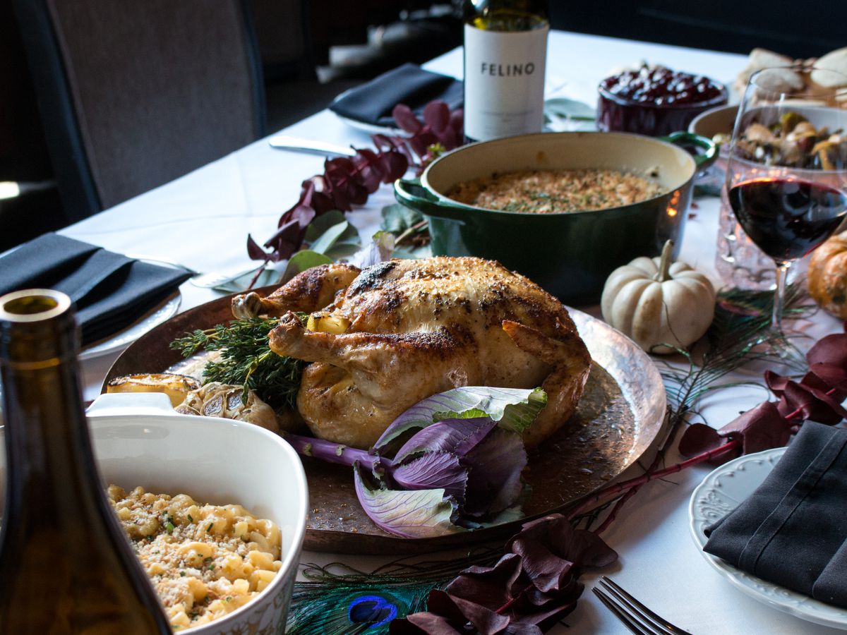 A table with a roasted turkey and bottles of wine.