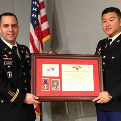 U.S. Army Lt. Col. Matthew Yandura and ROTC cadet Jay Choi hold Robert Mathis' Purple Heart medal and certificate Sunday, Nov. 13, 2016. The medal and certificate are to be presented to Mathis' relatives Sunday during a ceremony at the Holocaust Memorial Center Zekelman Family Campus in Farmington Hills, northwest of Detroit. Mathis was killed during World War II. Yandura found Mathis' Purple Heart certificate in 2013 in a used map shop in Jerusalem. 