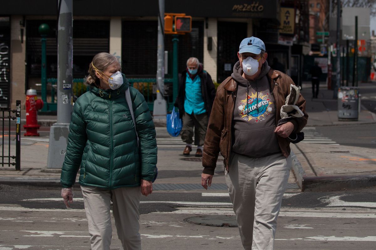 A couple wears N95 masks while walking along Houston Street during the coronavirus outbreak.