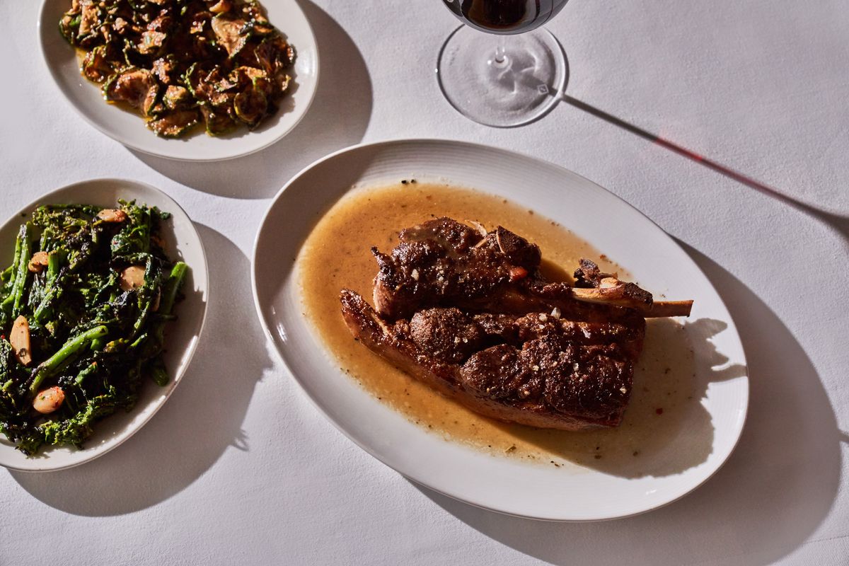 A plate of roasted lamb shoulder next to greens.