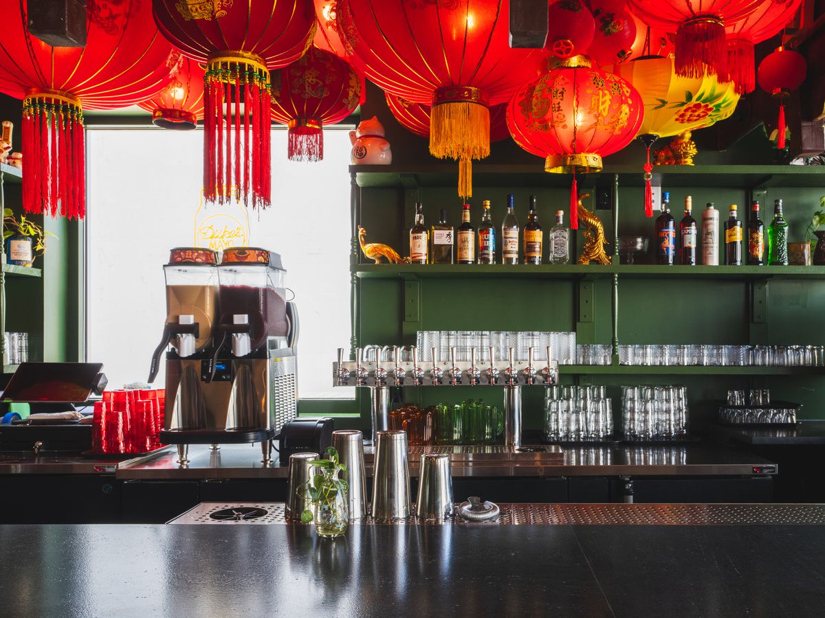 A green bar with red lanterns hanging overhead. 