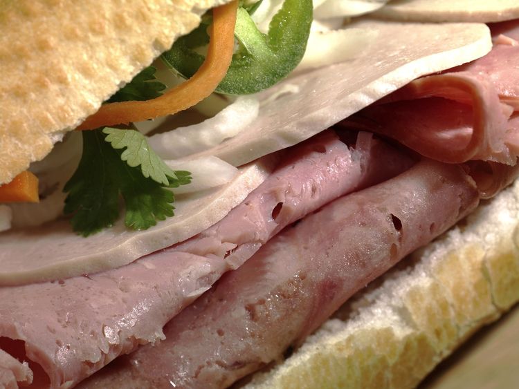 A banh mi sandwich loaded with pate, ham, head cheese, and pork roll.