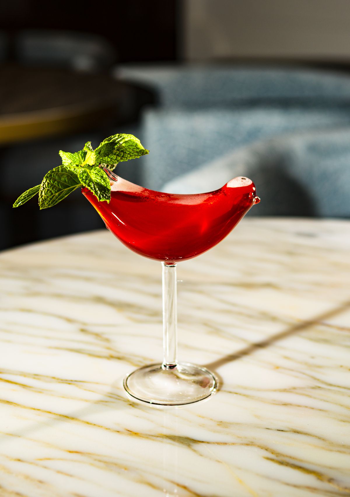 A red cocktail in a bird-shaped glass.