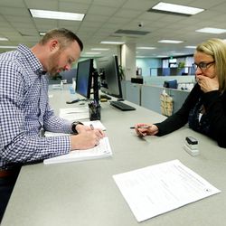 Herriman resident Justin Swain signs a referendum application as Earlene Pitt, executive assistant to Salt Lake County Clerk Sherrie Swensen witnesses it at the Salt Lake County Clerk's Office in Salt Lake City on Monday, June 11, 2018. Though officials have agreed to negotiate changes to the nearly 8,800-unit Olympia development near Herriman that's sparked outrage, concerned residents say the proposed referendum is a "plan C" if talks fall through.
