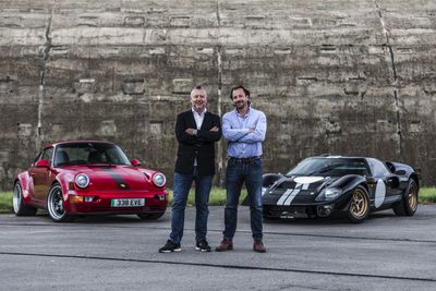 Red Porsche and black Ford GT40 sports car arranged behind two men posing cross-armed in jeans and button ups looking at the camera