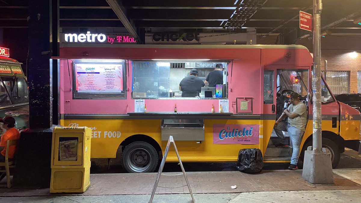 A pink and orange food truck is open for business on a Saturday night under Queens’s 7 train.