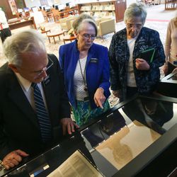 Sister Kathleen Harper, a missionary serving at The Church of Jesus Christ of Latter-day Saints' Church History Library, second from left, talks to Tom Savoldi, left, and Pia Savoldi, third from left, as they view pages from the printer's manuscript of the Book of Mormon at the library in Salt Lake City on Thursday, Sept. 21, 2017.