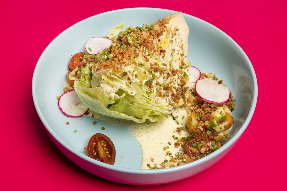 A round blue bowl holds a wedge salad.