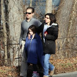 Parents walk away from the Sandy Hook School with their children following a shooting at the school Friday, Dec. 14, 2012.