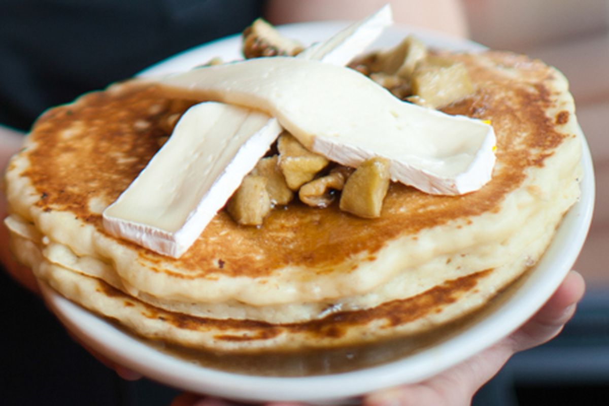 Giant pancakes topped with slices of brie place in a cross on top of chopped walnuts. 