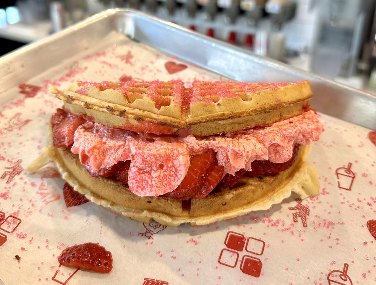A waffle folded in half and stuffed with strawberries and sweet cream, and topped with red sprinklers.