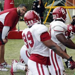 Oklahoma defensive line coach Jerry Montgomery, left, works out his players during a spring NCAA college football practice in Norman, Okla., Tuesday, March 12, 2013. Montgomery and other Oklahoma coaches are attending the All-Poly camp in Layton, Utah this weekend.