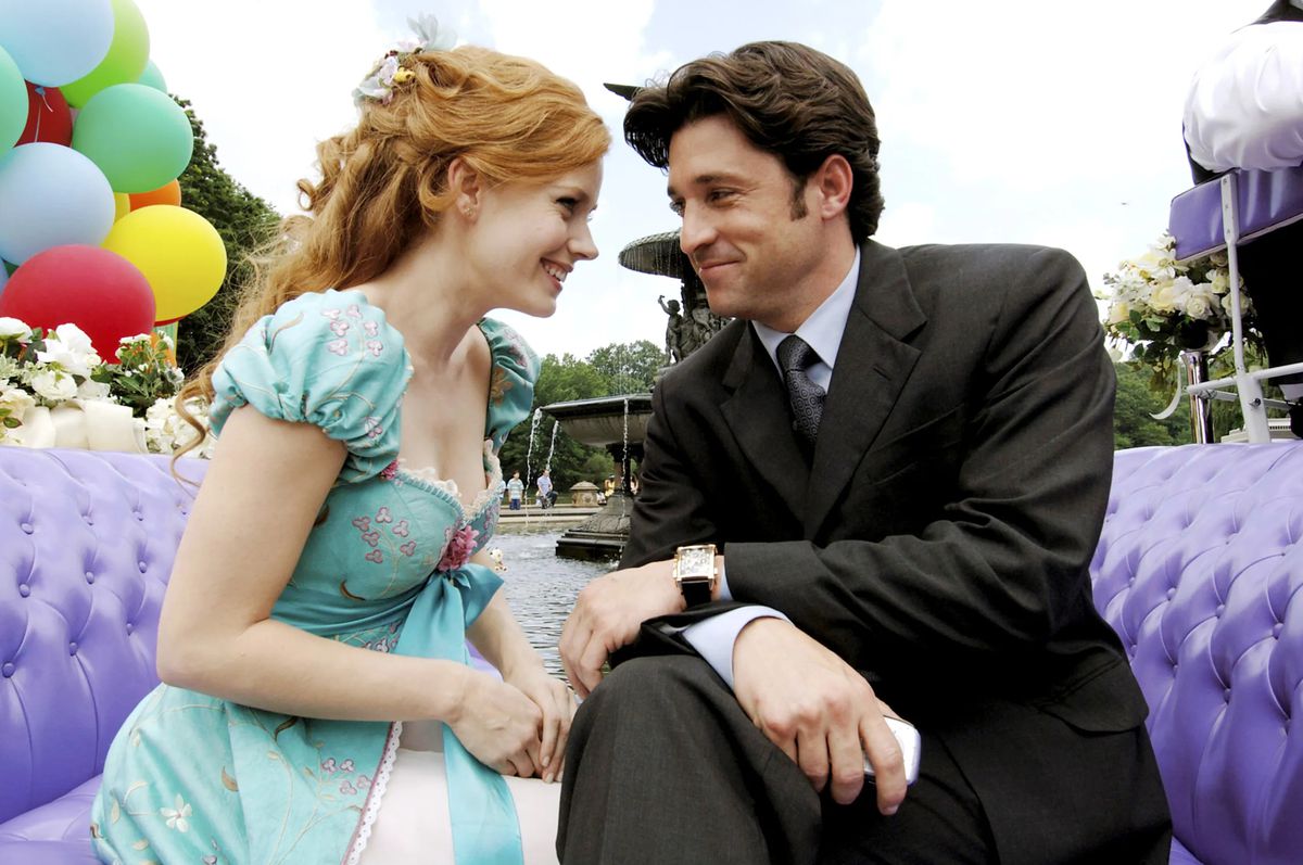 Live-action Disney Princess Giselle (Amy Adams) and love interest Robert (Patrick Dempsey) sit smiling with their heads together in a purple-upholstered coach riding around a New York City park in Enchanted
