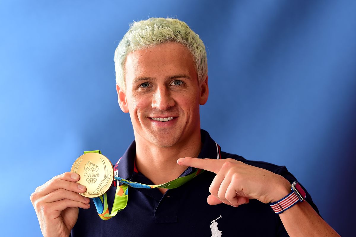 Ryan Lochte points at his gold medal.