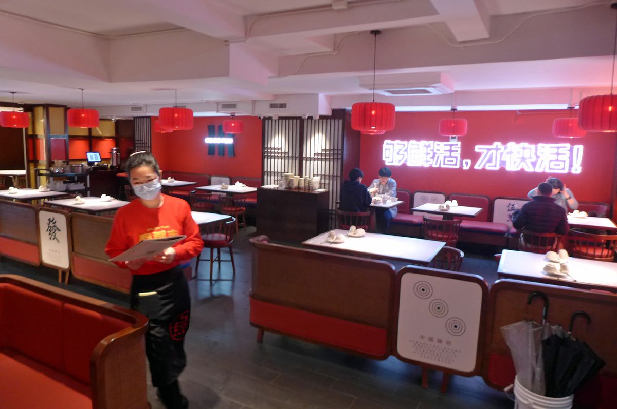 A red restaurant interior with red walls and booths and a waitress dressed in red dashing to one side.