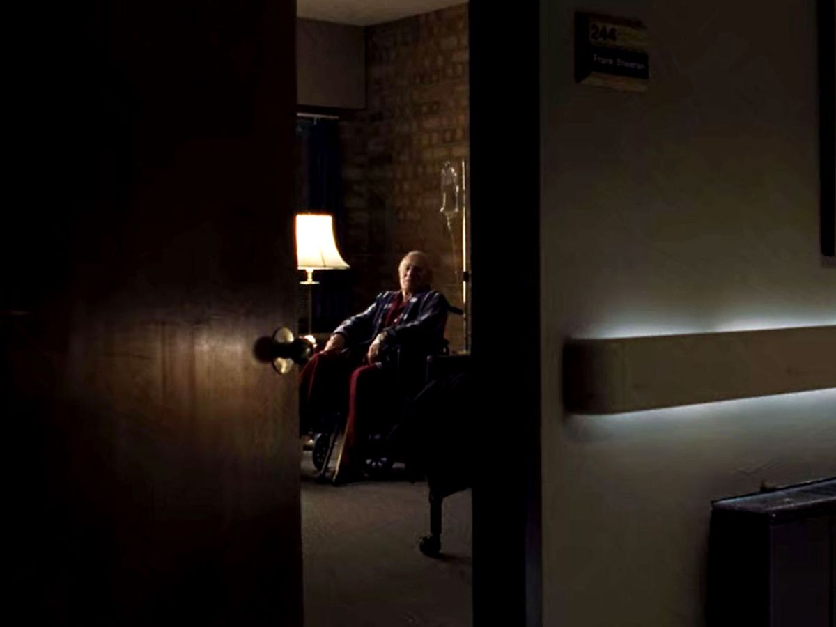 An old man is seen through a half-open door.