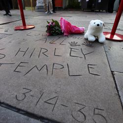 Flowers and a stuffed animal are left at the hand and foot prints for Shirley Temple Black at the TCL Chinese Theatre in the Hollywood section of Los Angeles on Tuesday, Feb. 11, 2014.