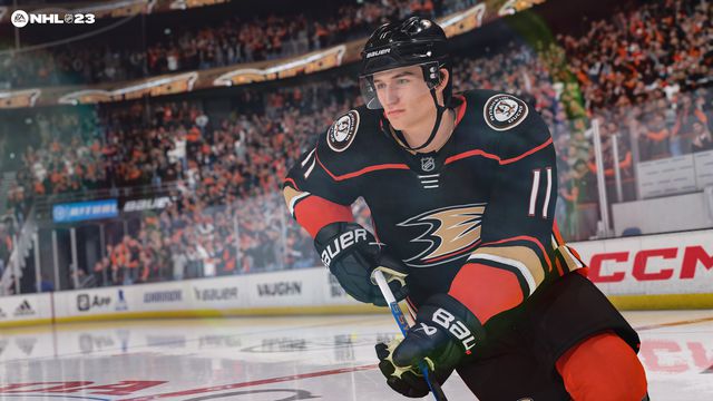 a screenshot of Trevor Zegras, #11, skating with the puck wearing the Anaheim Ducks’ black and orange home jersey in NHL 23