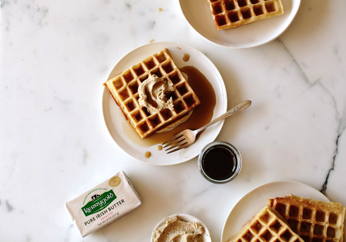 Plates of waffles next to a package of Kerrygold butter