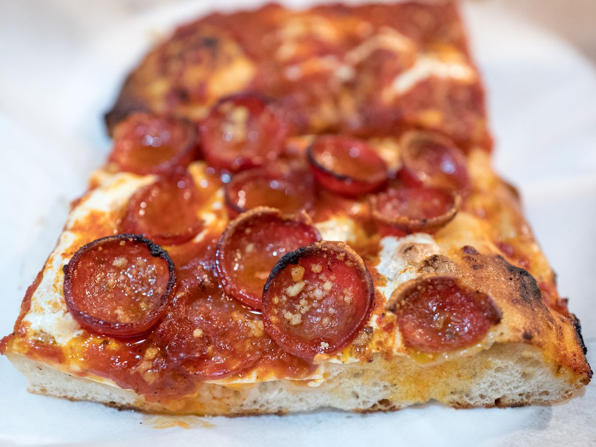 A square slice of Prince Street pepperoni pizza sits on white paper
