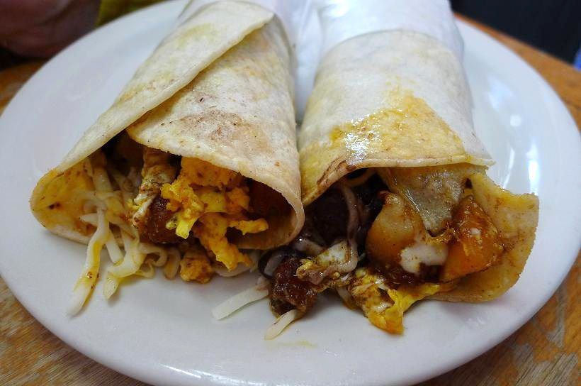 A pair of tacos rolled inside tissue paper.