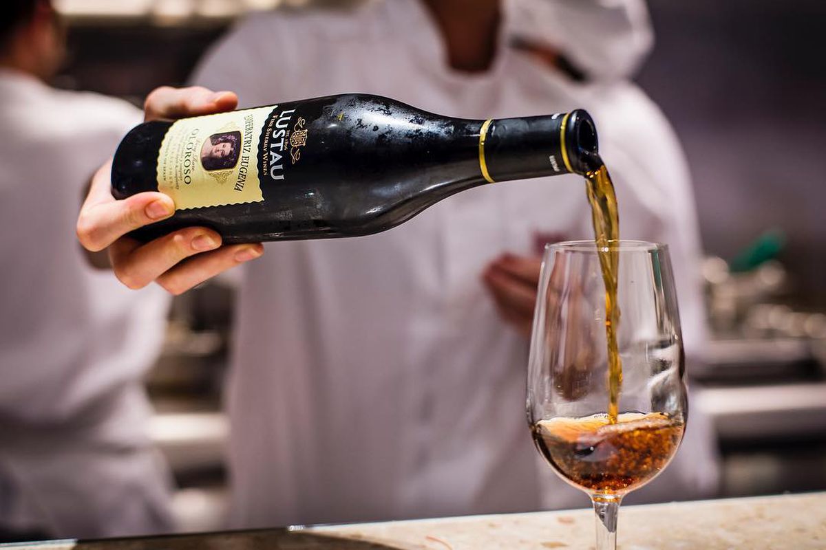 Pouring a bottle of Oloroso sherry into a glass on a marble bar at Barrafina Drury Lane