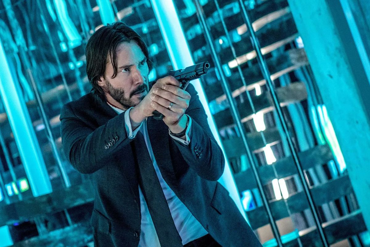 An image of Keanu Reeves as John Wick, aiming a handgun.