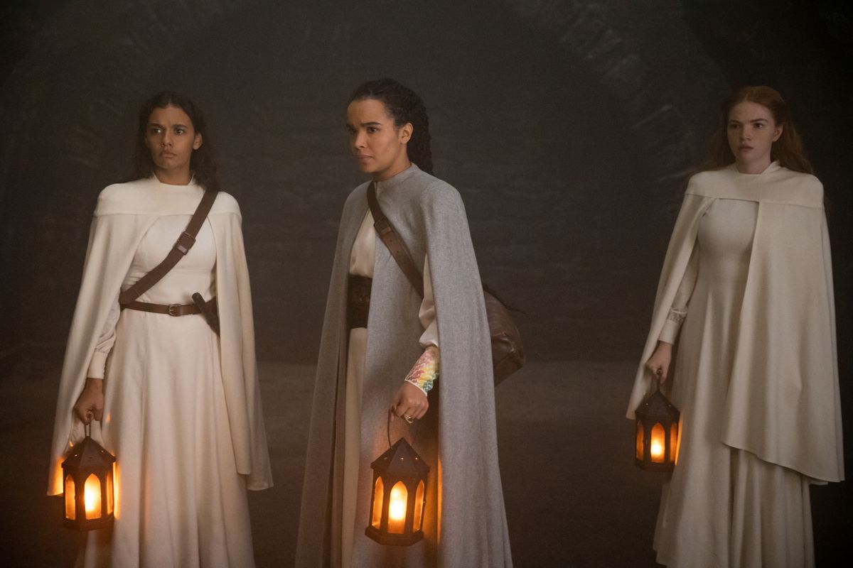 Nynaeve (Zoë Robins), Egwene (Madeleine Madden), and Elayne (Ceara Coveney) stand with lanterns looking at something 