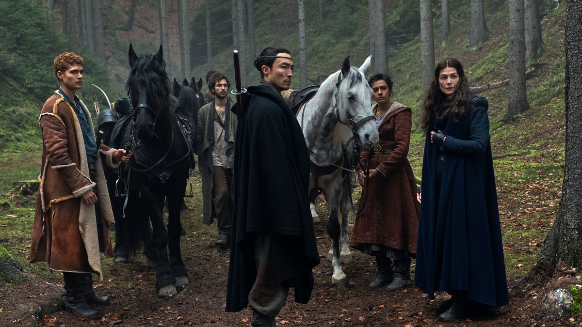 The heroes of The Wheel of Time, standing with their horses and looking off at people standing past the camera, in a season 1 still from the show