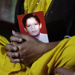 In this Monday, March 25, 2013, photo, Pravesh Kumari Singh, 36, sits with a photo of her son Pankaj, 14, who went missing in 2010, in her house in New Delhi, India. Pankaj is among the more than 90,000 children who go missing in India each year. More than 34,000 of them are never found, the government said last year. (AP Photo/Manish Swarup)
