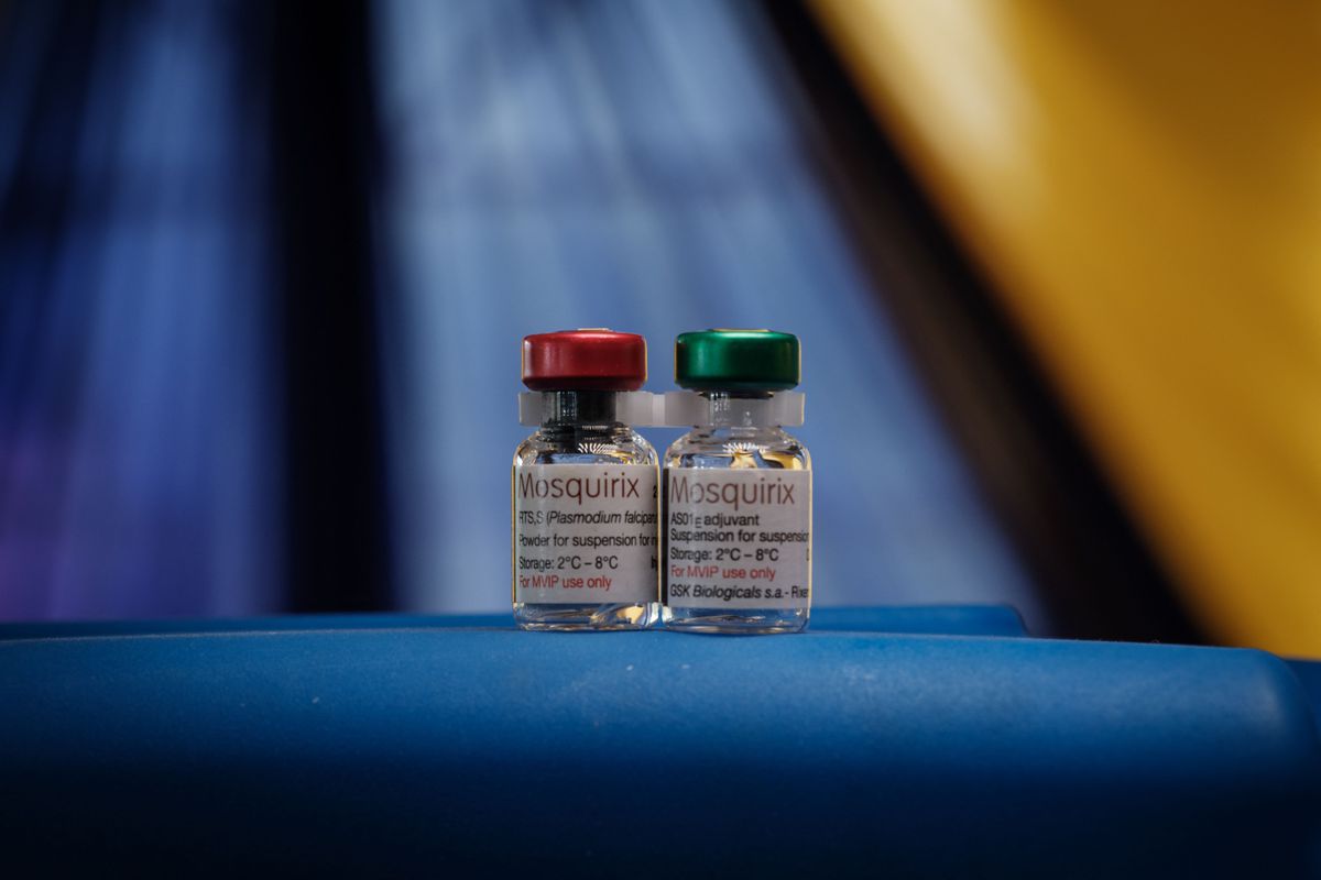 Two small vials of vaccine sitting on a blue table.