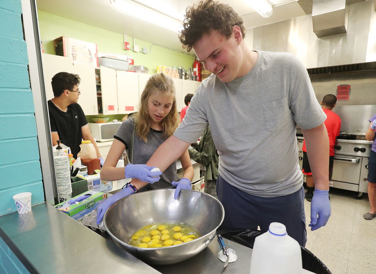 Teen volunteers Laine Riley and Nick Altman crack eggs to make breakfast burritos at the Sugarhouse Boys and Girls Club to feed the homeless in Salt Lake City, Utah, on Thursday, July 18, 2019.