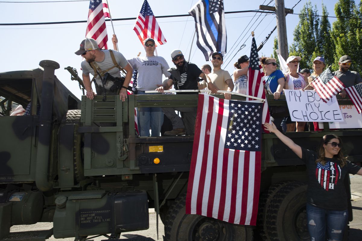 People in the back of a truck waving a flag and yelling in a protest.