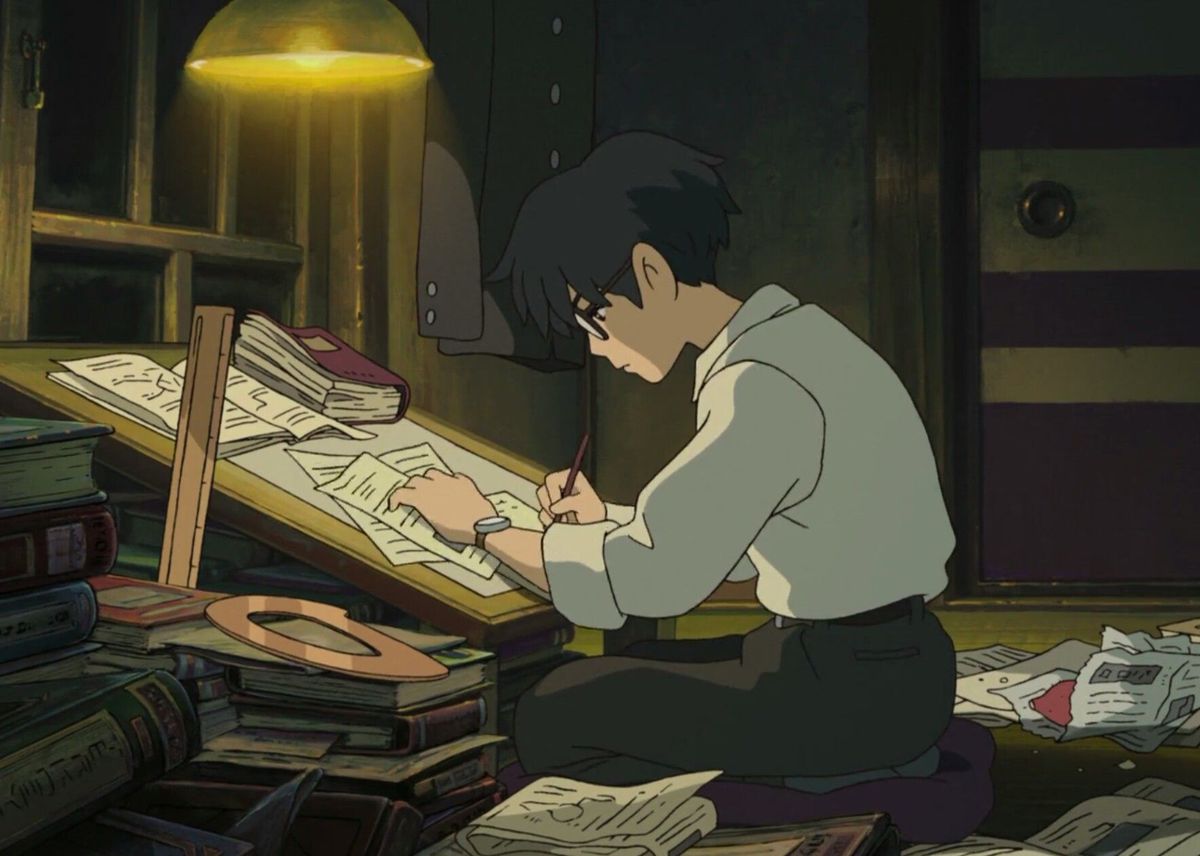Jiro working at his drafting desk lit by one overhanging light in The Wind Rises