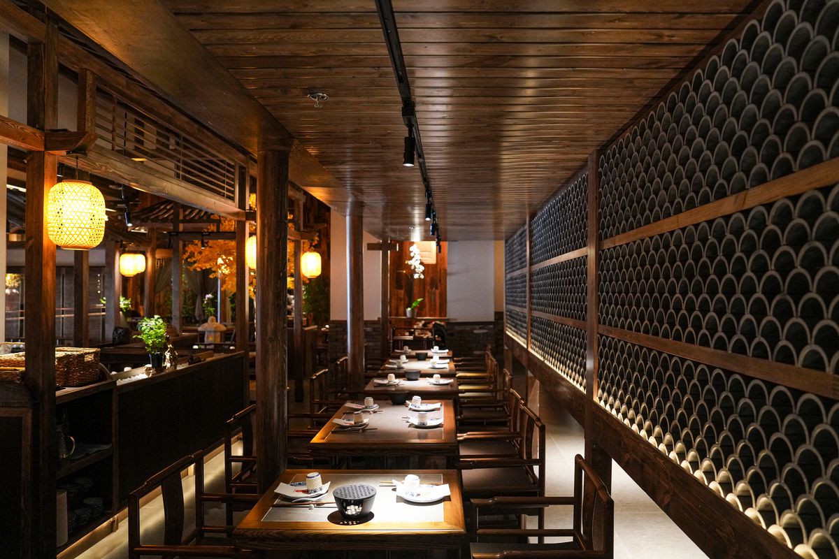 An interior of a restaurant with wooden tones and lanterns.